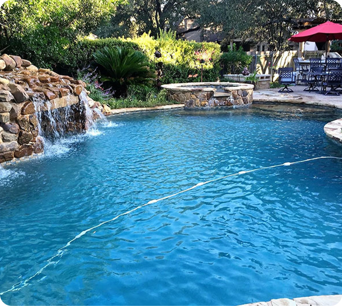 swimming pool surrounded by lush trees and a small waterfall